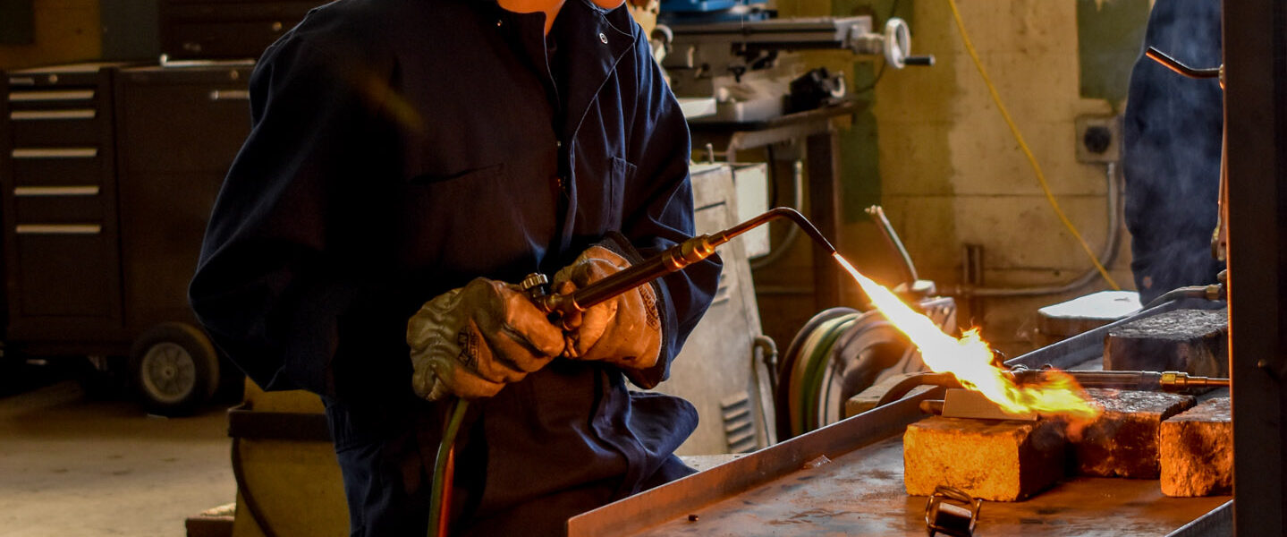 The fire from the blow torch is shining on the girl as she begins the process of welding. This photo was shot with a D3500 camera and a zoom lens.